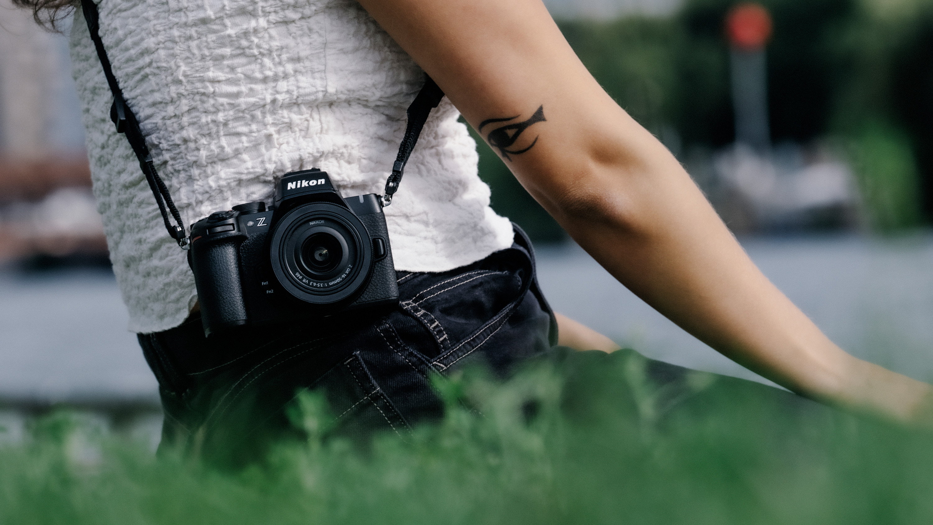 Nikon Z50 II mirrorless camera slung over someone's shoulder and resting by their hip